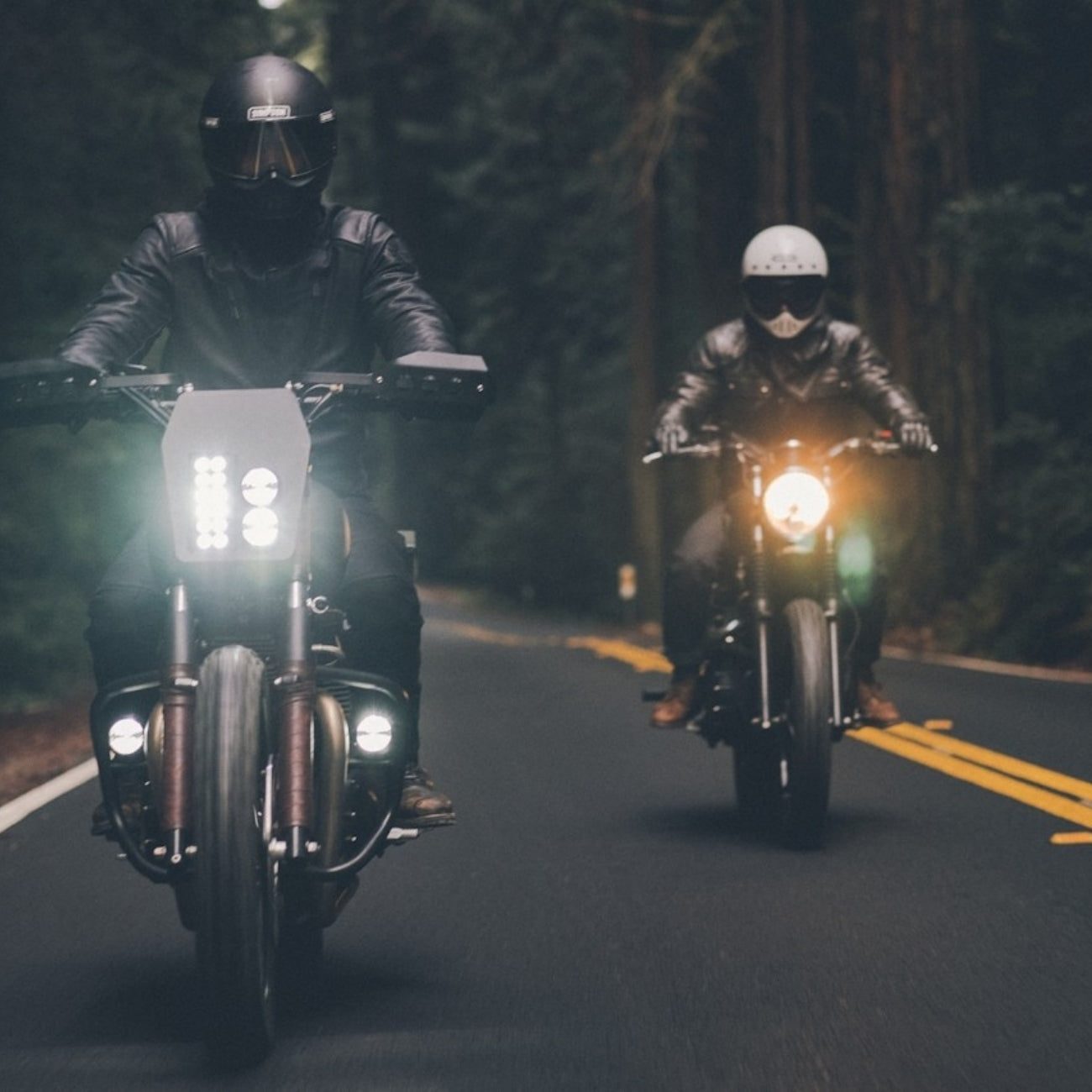 Two motorcyclists on a dark road with trees in the background wearing the earpeace motorcycle earplug