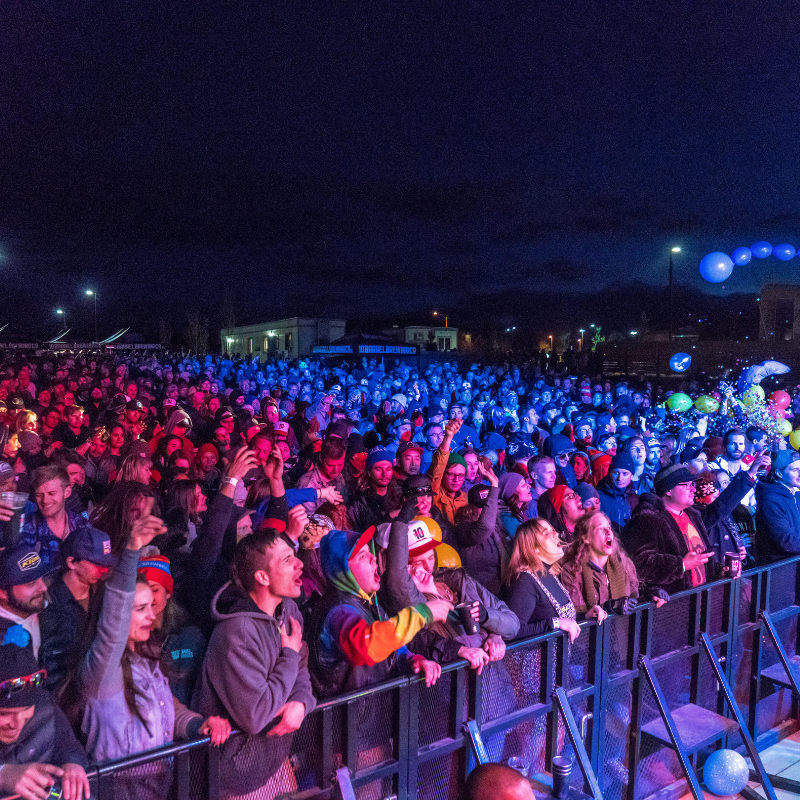 Large crowd at a nighttime outdoor event wearing EARPEACE concert earplugs