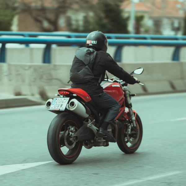 Person riding a red motorcycle on a road with a blurred background