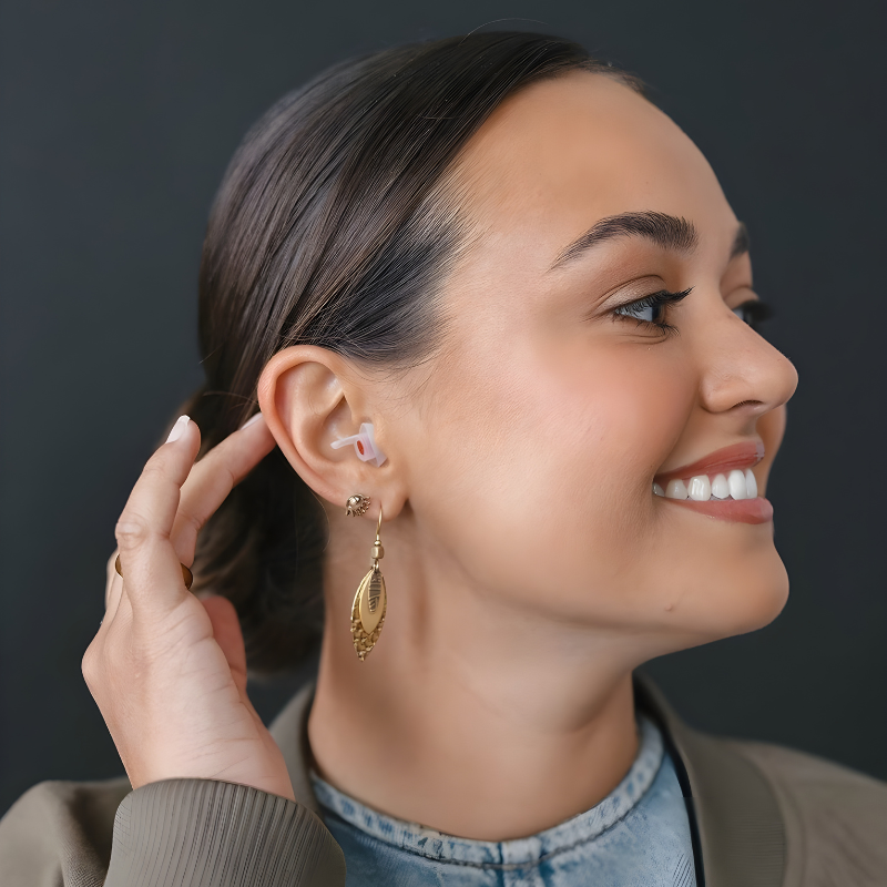 Woman wearing a gold earring against a dark background with EARPEACE Music earplug in ear