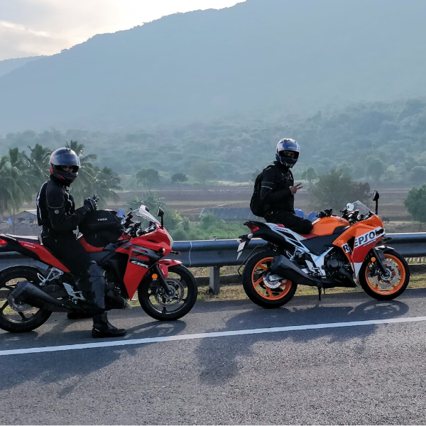 Two motorcyclists on a scenic road with mountains in the background
