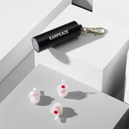 Black 'EARPEACE' container with earplugs on a white surface